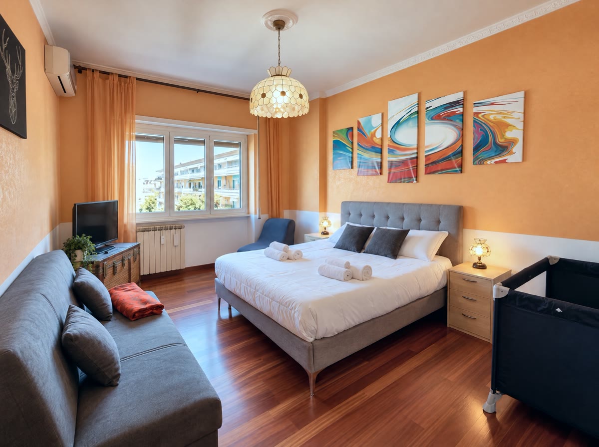 Camera matrimoniale con pareti arancio, divano letto e lettino