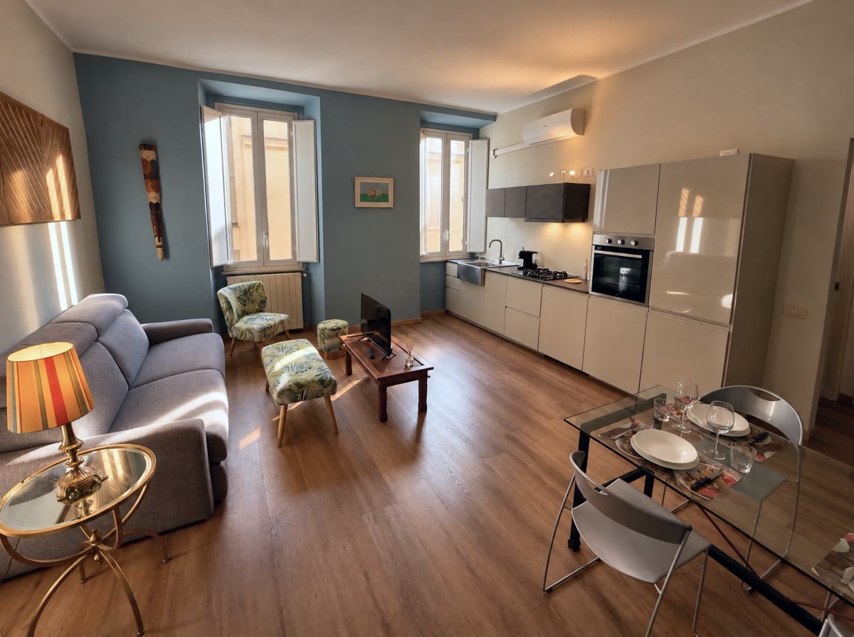 Soggiorno con cucina a vista, divano grigio e pareti azzurre
